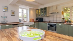A modern kitchen with green cabinets, a wooden countertop, a built-in oven, and a large window providing natural light. - 5 Person Holiday Home in Lundby (Lundby)