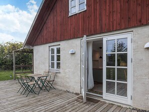 A wooden deck with outdoor furniture, a large open door leading to a room, and a red barn-like structure. - 5 Person Holiday Home in Lundby (Lundby)