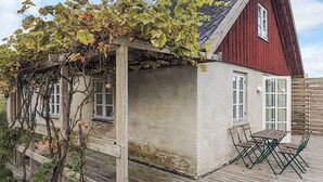A rustic building with a sloped roof, a wooden pergola with vines, and a small patio with outdoor furniture. - 5 Person Holiday Home in Lundby (Lundby)