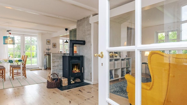 A modern living room with a fireplace, wooden flooring, and a yellow armchair. - 5 Person Holiday Home in Lundby (Lundby)