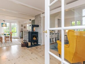 Un salon moderne avec une cheminée, un plancher en bois et un fauteuil jaune.