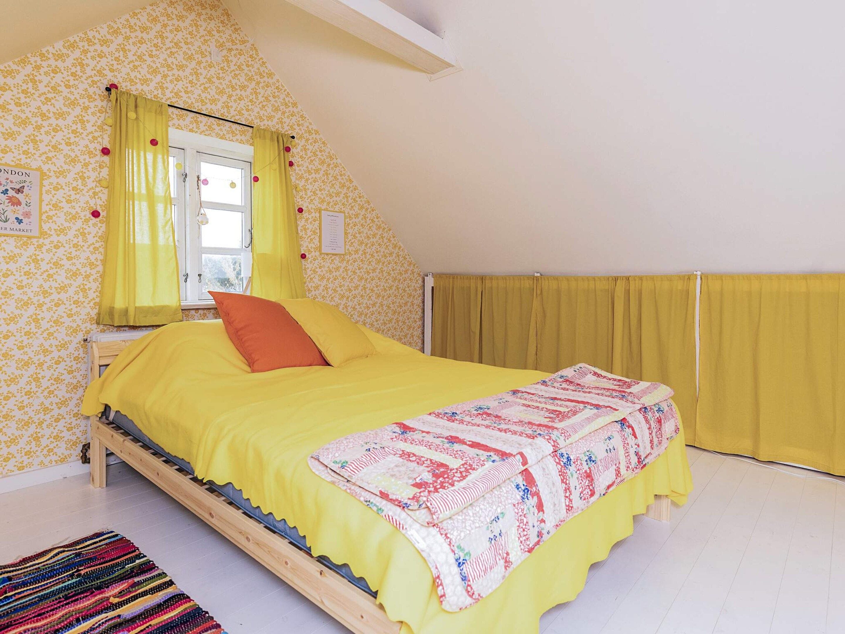 A bedroom with a bed, a window, and a curtain.