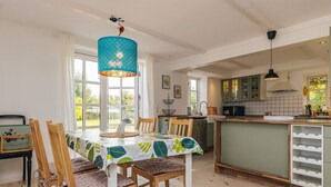 A dining area with a table set for four, wooden chairs, a hanging light fixture, and a view of the kitchen through large windows. - 5 Person Holiday Home in Lundby (Lundby)