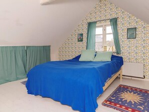 A bedroom with a bed, curtains, a window, and a patterned wall. - 5 Person Holiday Home in Lundby (Lundby)