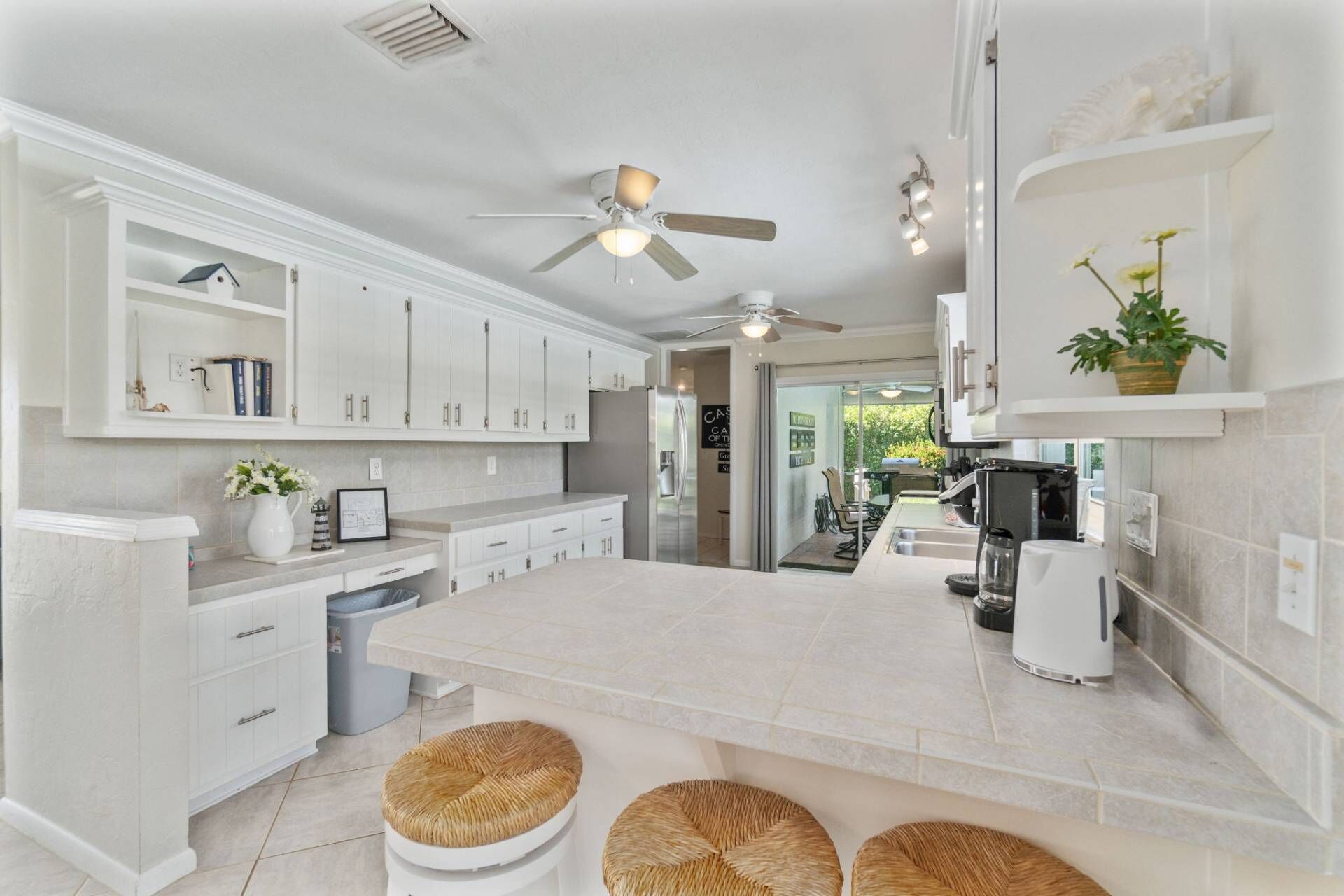 A modern kitchen with white cabinetry, a central island, and a ceiling fan.
