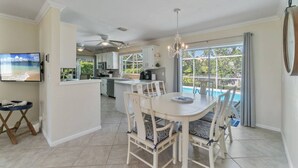 Una cocina amplia con comedor, ventanas grandes y ventilador de techo.