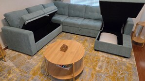 Una sala de estar moderna con un sofá modular gris, un sofá cama y una mesa de centro de madera.