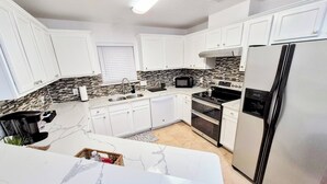 Una cocina moderna con armarios blancos, salpicadero con azulejos blanco y negro, refrigerador de acero inoxidable y estufa negra.