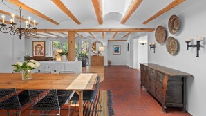 Eine geräumige Küche mit einem Holztisch, Stühlen, einem Holzschrank und einer Kristallleuchter.