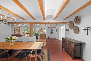 Eine geräumige Küche mit einem Holztisch, Stühlen, einem Holzschrank und einer Kristallleuchter.