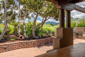 Un patio al aire libre con borde de ladrillo, cubierta de madera y una jardinera de piedra.