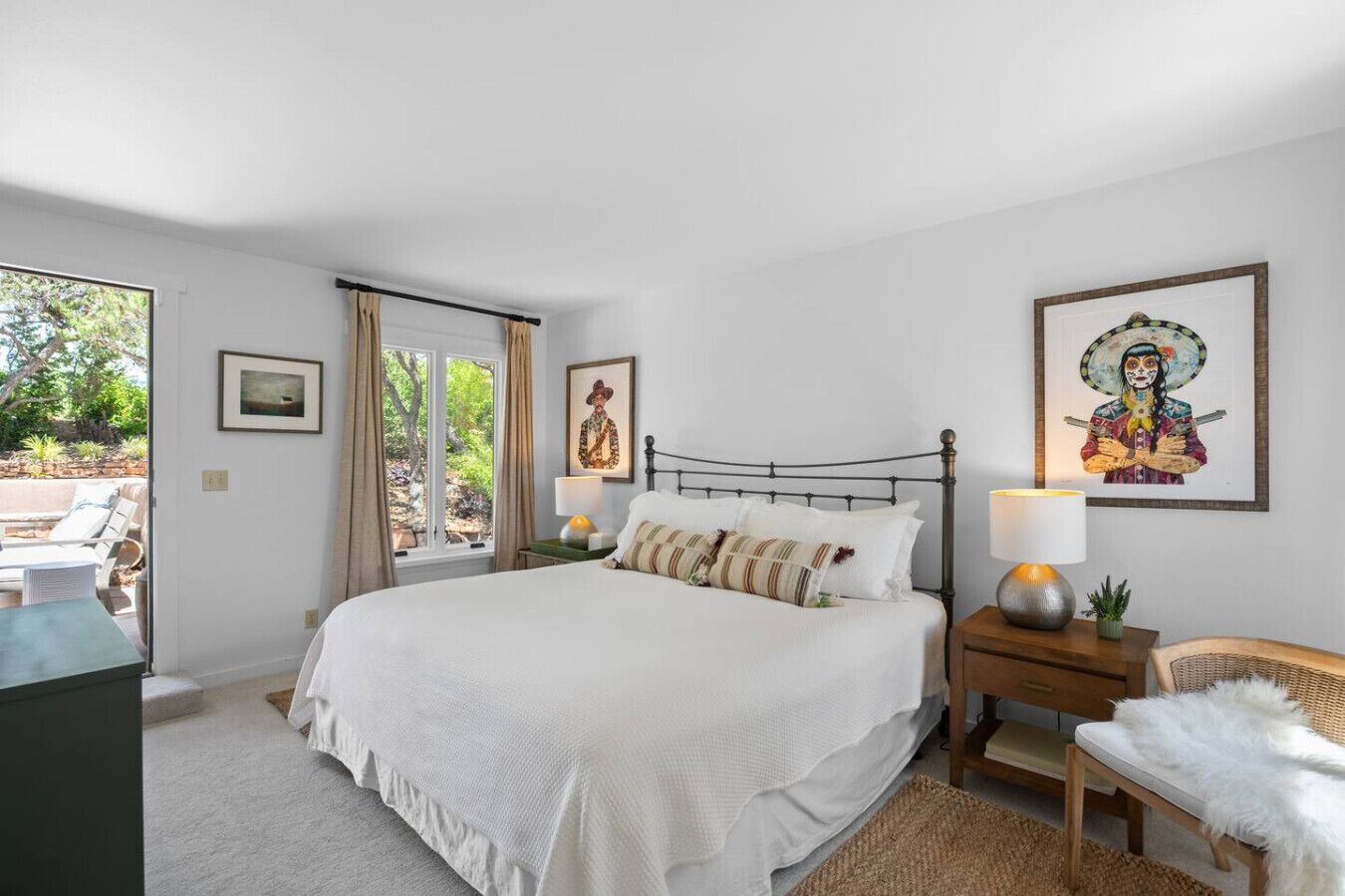 A bedroom with a bed, bedside tables, a chair, and artwork on the walls.