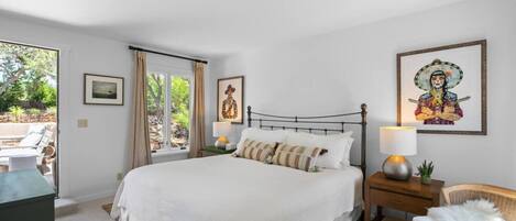 A bedroom with a bed, bedside tables, a chair, and artwork on the walls.