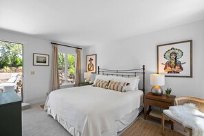 Een slaapkamer met een bed, nachtkastjes, een stoel en kunst aan de wanden.
