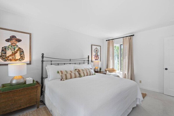 Un dormitorio con una cama, una mesita de noche, una lámpara y un marco de fotos en la pared.