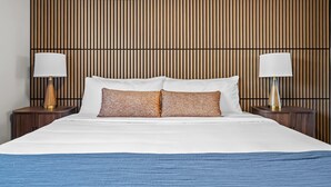 Een hotelkamer met een bed, twee nachtkastjes en een houten hoofdbord.