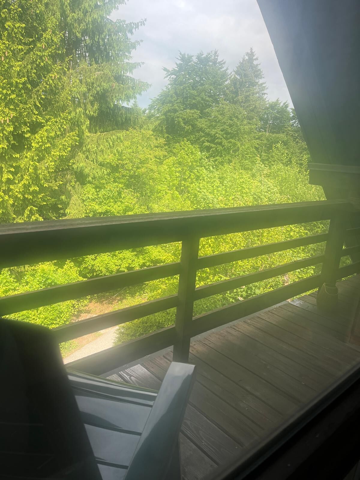 A wooden deck with a railing overlooking a lush green landscape.