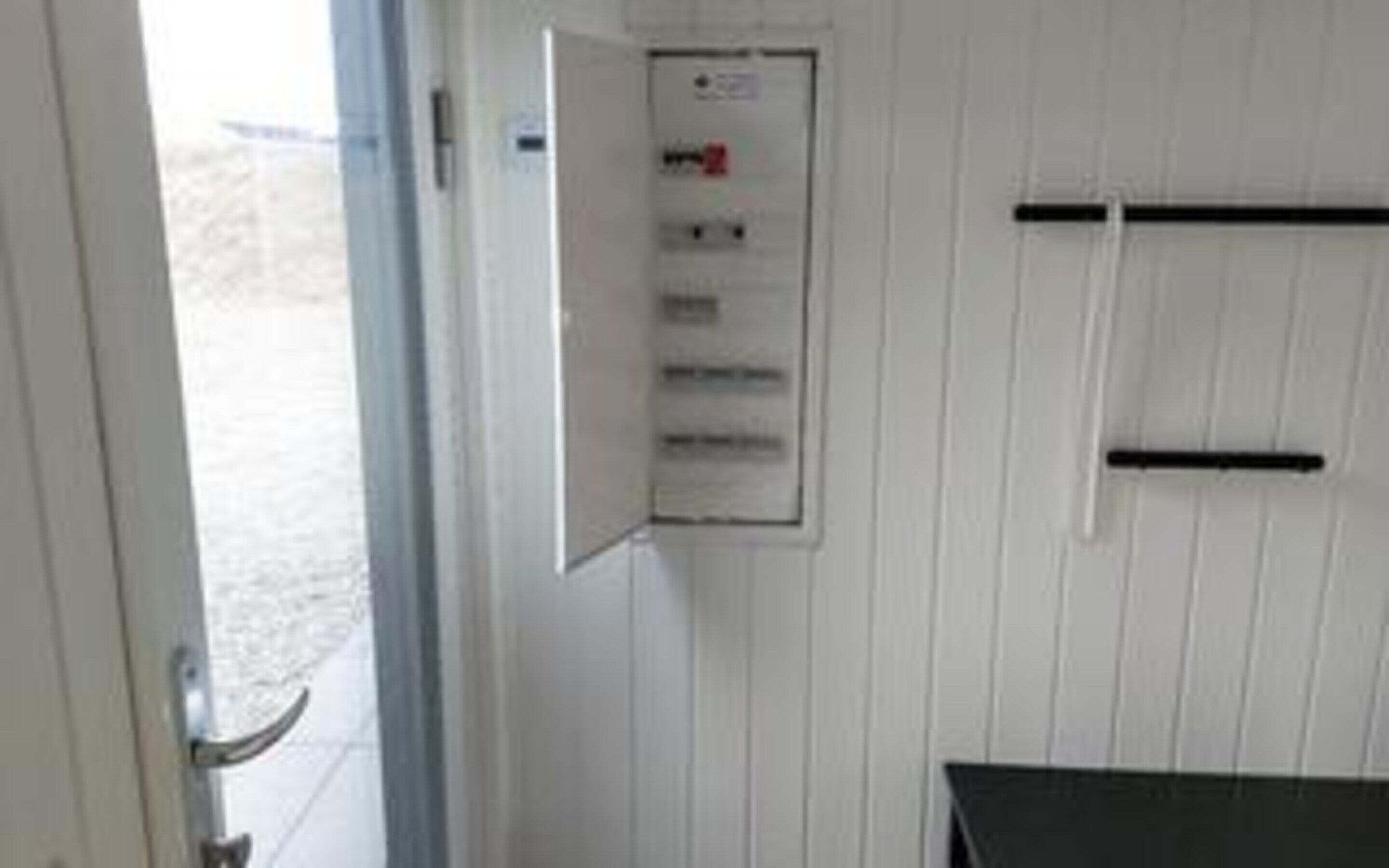 Une pièce avec un mur blanc, une porte et un tableau blanc sur lequel on peut écrire, avec du texte dessus.