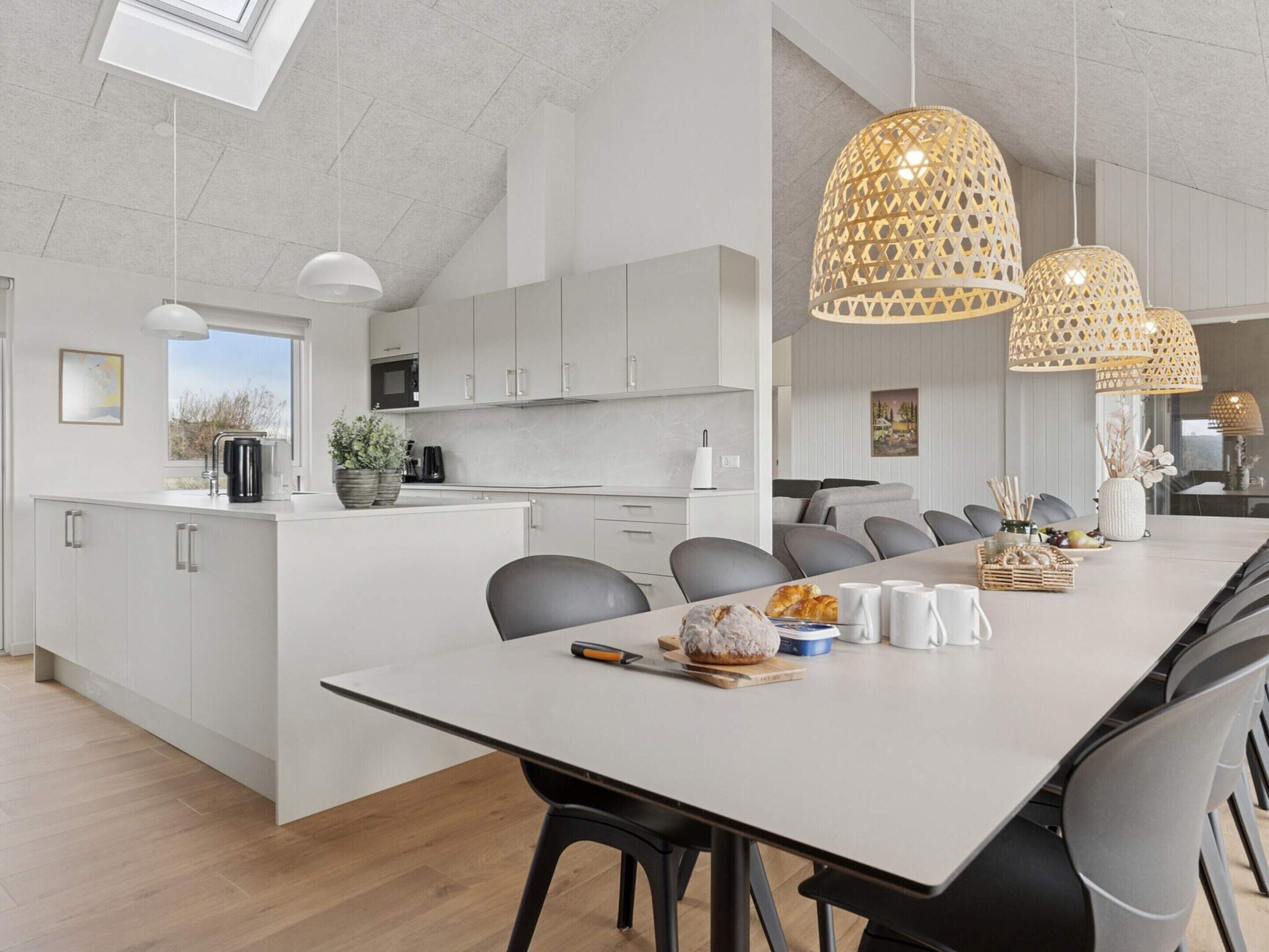 Una cocina moderna con armarios blancos, una isla grande e iluminación colgante.