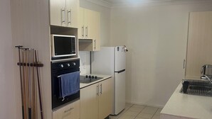 A compact kitchen with a microwave, oven, and refrigerator.