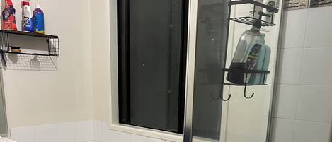 Un baño moderno con ducha envuelta en vidrio, una bañera blanca y una ventana sobre el lavabo.