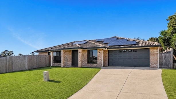 A residential house with a garage, a paved driveway, and a well-maintained lawn.