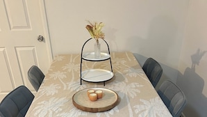 A dining table with a floral tablecloth, a tiered candle holder, and a wooden tray with candles.