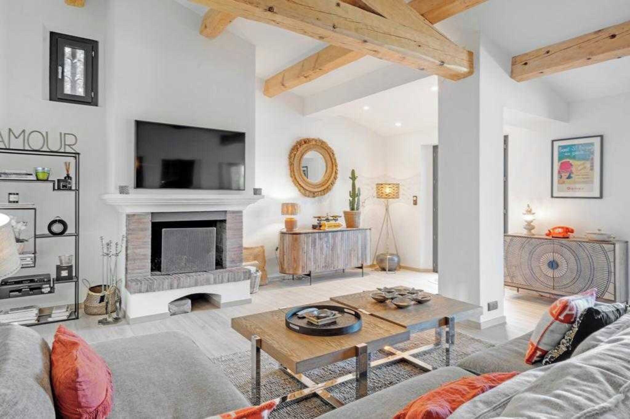 Un salon moderne doté d’une cheminée, d’un téléviseur fixé au mur et d’un coin repas avec une table et des chaises.