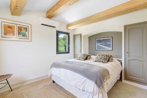 A bedroom with a bed, a chair, a door, and a window.