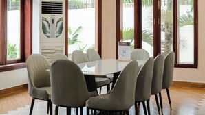 Un comedor espacioso con techo alto, ventanas grandes y una mesa central rodeada de sillas.