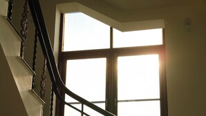 Una escalera con barandillas ornamentadas y un ventanal con persianas.