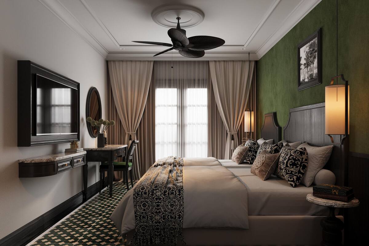 A hotel room with a large bed, a desk with a chair, a ceiling fan, and a large window with curtains.