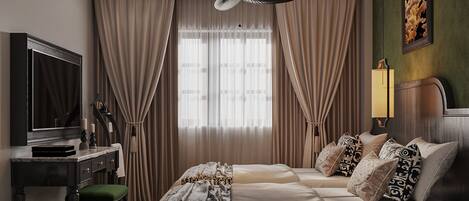 A hotel room with a bed, a desk, a chair, a television, and a ceiling fan.