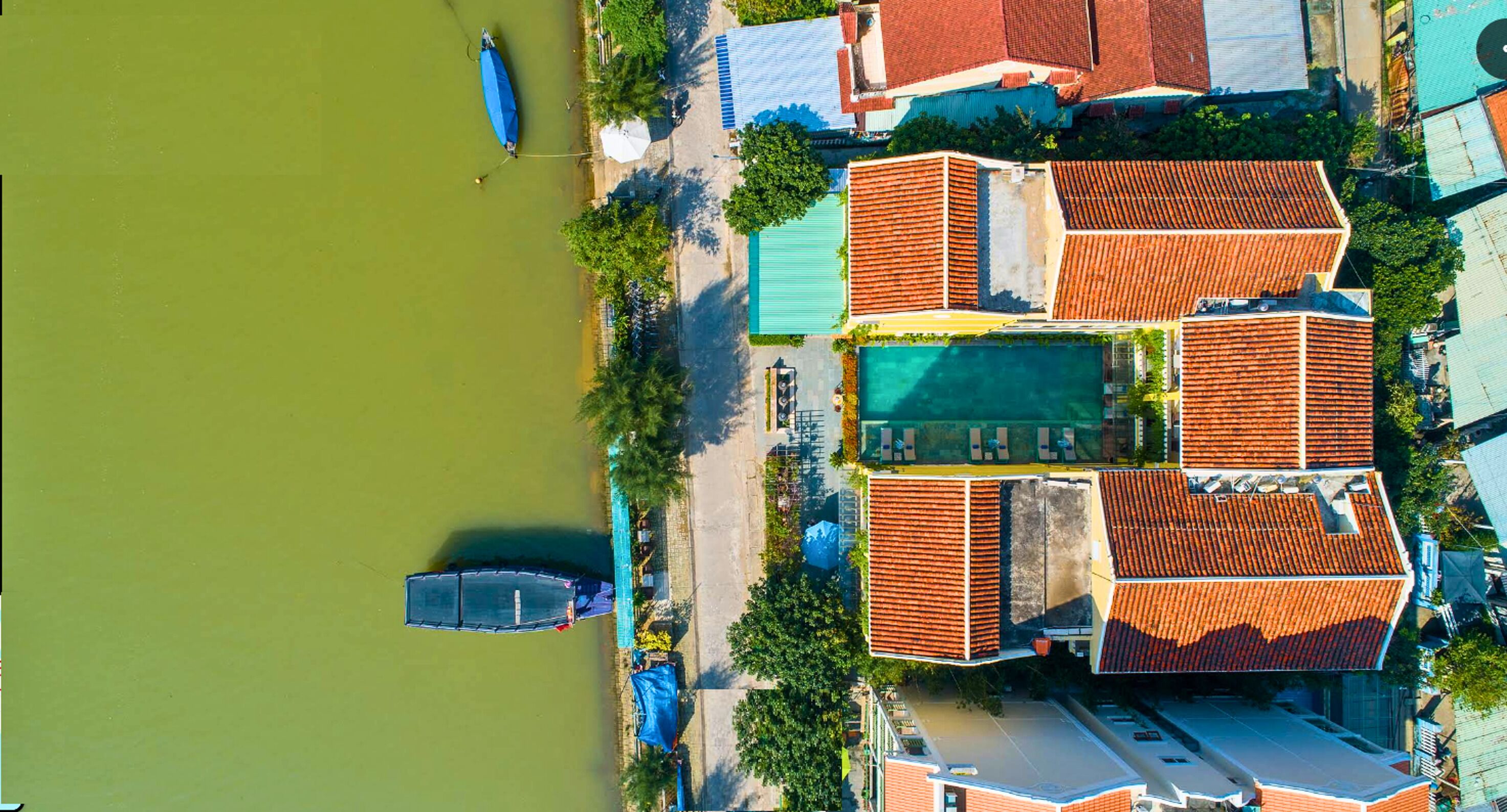 An aerial view of a coastal area with buildings, a swimming pool, and a boat dock.