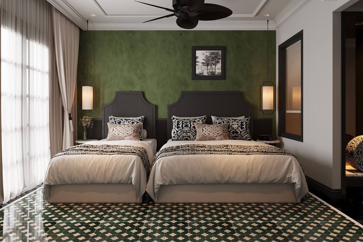 A hotel room with two beds, a ceiling fan, a green accent wall, and patterned bedding.