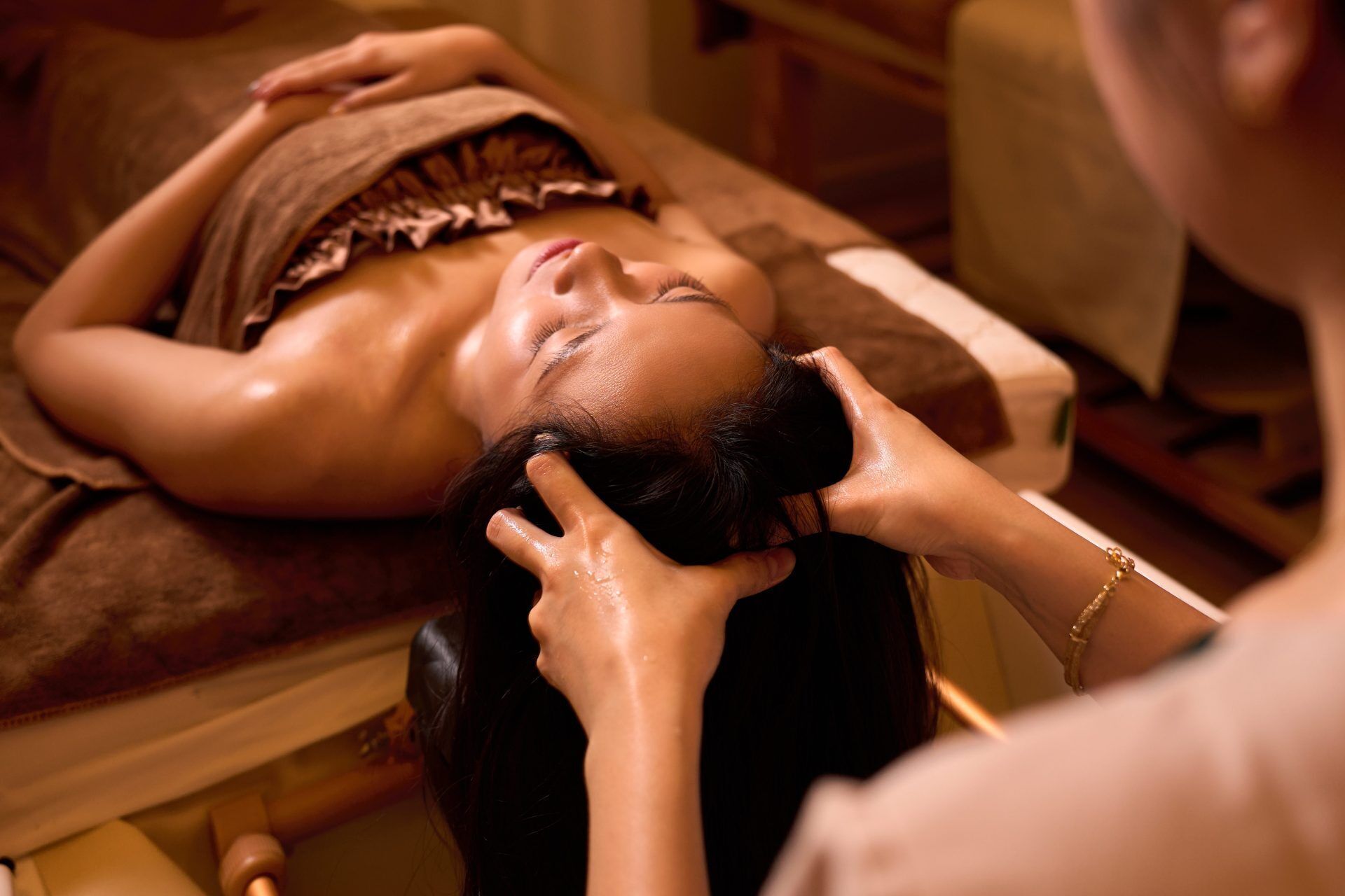 En person ligger på en massagestol og modtager en hovedmassage.