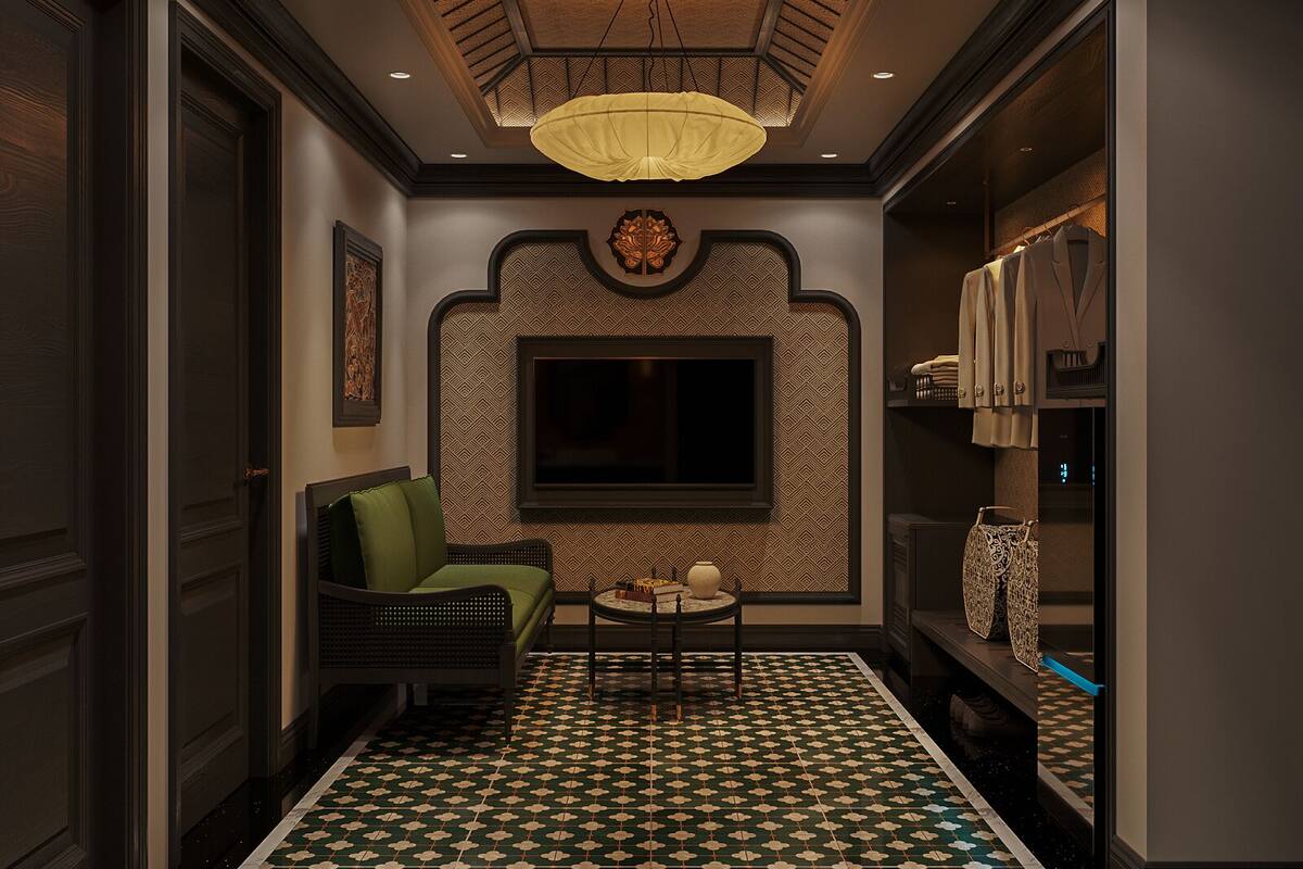 A hallway with a patterned floor, a green armchair, a small table with a vase, and a TV mounted on the wall.