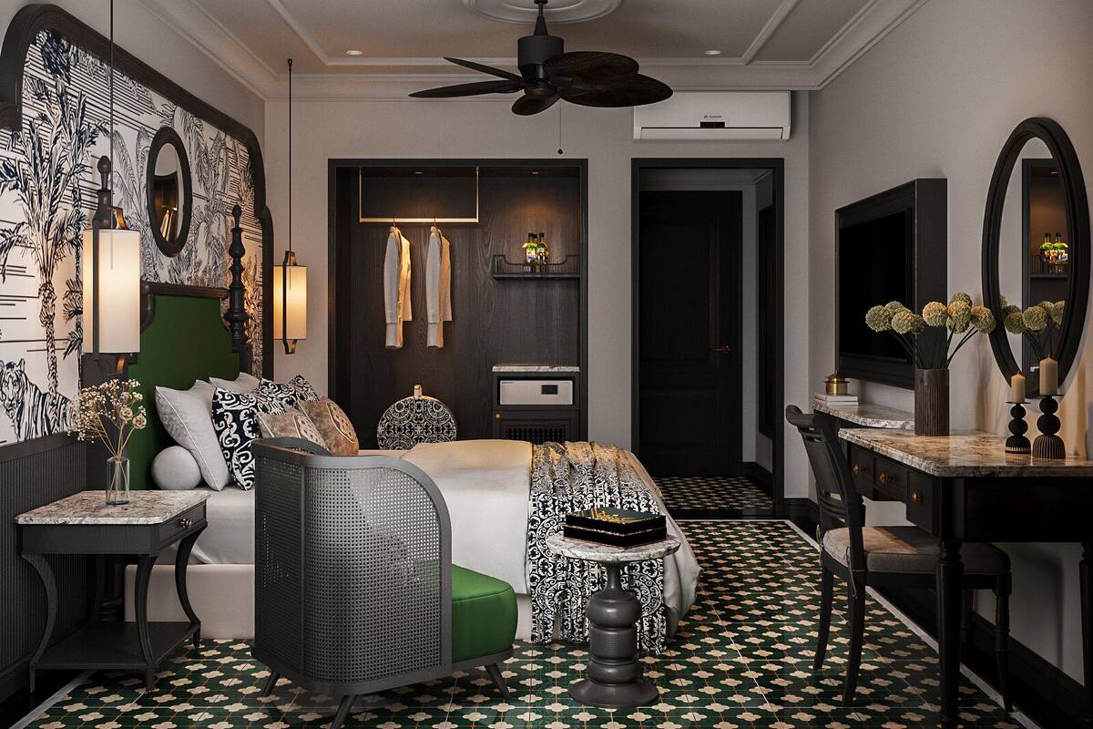 A modern hotel room with a large bed, a desk, a chair, a mirror, and a ceiling fan.