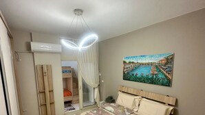 A bedroom with a bed, a nightstand, a wall-mounted painting, and a ceiling light fixture.