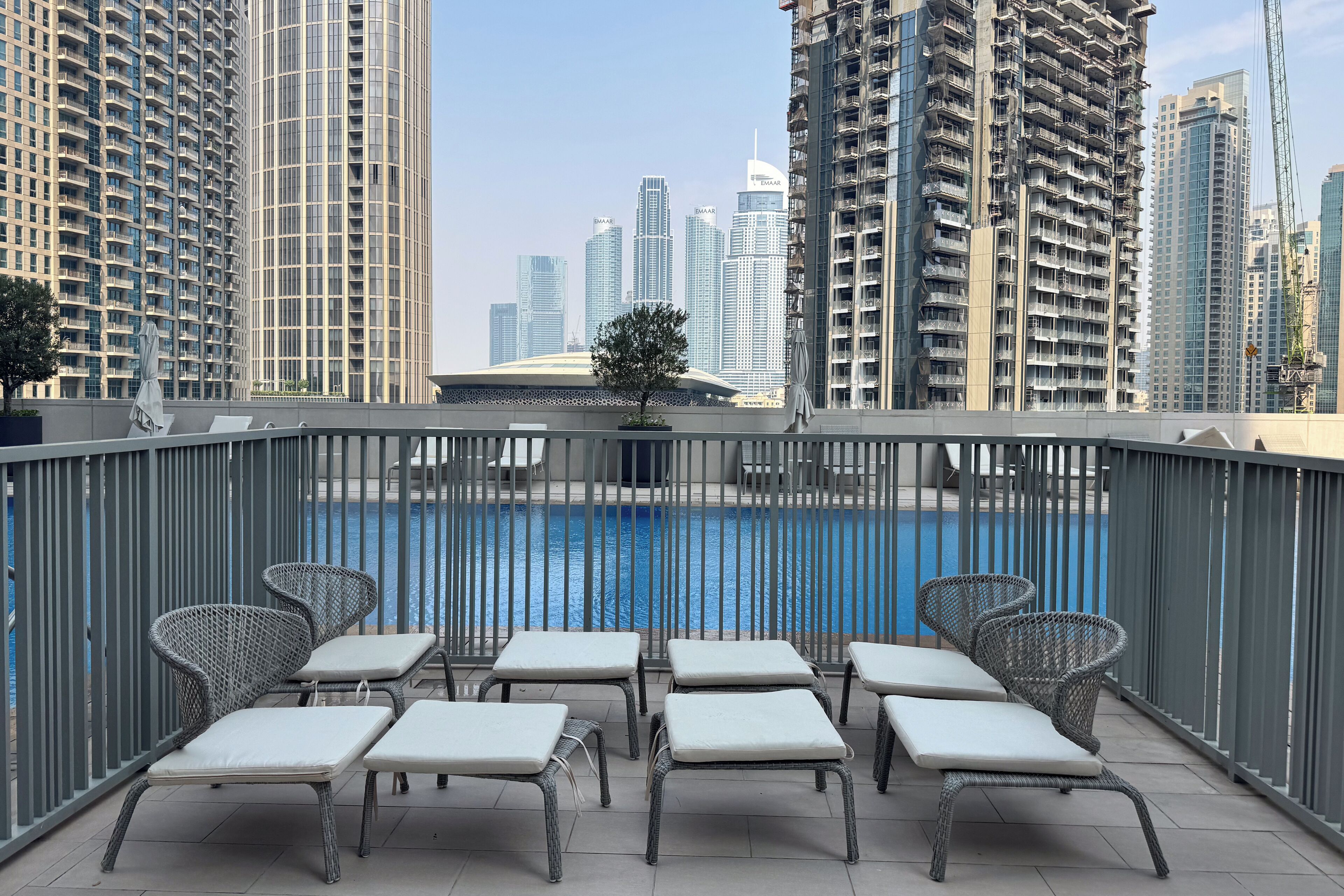 Een balkon met lounge fauteuils en een zwembad.