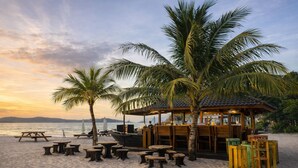 A beachside restaurant with outdoor seating, palm trees, and a view of the sea. - Seaside Cenang (Langkawi)