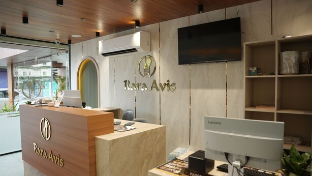 A reception desk with a wooden finish, a mounted television, and a Lenovo computer monitor.