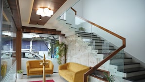 A modern living room with a staircase, a sofa, a coffee table, and a red rug.