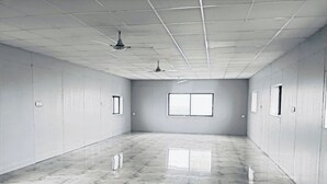 Una habitación amplia con suelo de mármol, un ventanal grande y ventiladores de techo.