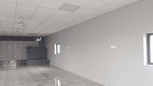 Una habitación amplia y vacía, con techo de azulejos, pared con diseño y suelo de mármol.