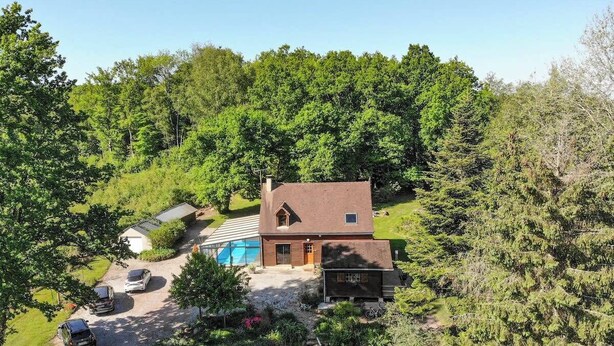 A house with a swimming pool, surrounded by dense forest.