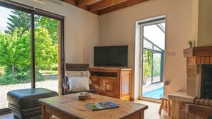 A living room with a television, a fireplace, and a large window overlooking a garden.