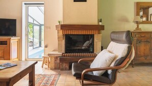 A living room with a fireplace, a television, a sofa, and a dining table.