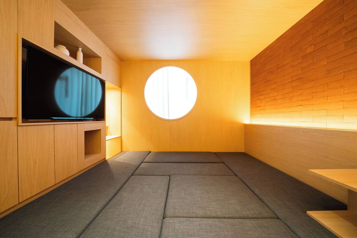 Ein modernes Interieur mit einer Holzwand, einem Rundfenster und einem Flachbildfernseher auf einem Holzkasten.