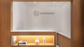 A minimalist interior with a wooden panel design, a white reception desk, and a logo above it.